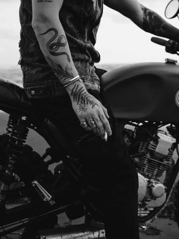 Crop anonymous hipster smoking cigarette on motorbike outdoors